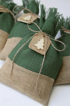 three burlap bags tied with twine and decorated with wooden christmas tree tags