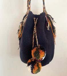 a handbag hanging from a hook on a wall with two pom poms attached to it