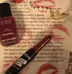 an open book with lipstick on it next to a bottle of chanel nail polish