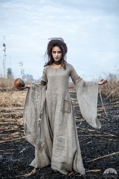 a woman in a long dress holding two balls and standing on the ground with her arms outstretched