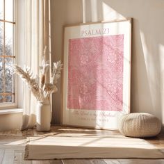 a vase with some flowers next to a poster on the wall in front of a window