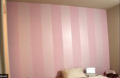 a pink and white striped wall in a bedroom with a small child's bed