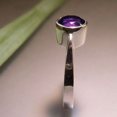 "A stylish, royal purple amethyst that is 8mm, or about 5/16\" in diameter. I hand carve this ring in wax, and then cast it using the lost wax process. Hand carving allows for a much more sculptural feel to the ring. The stone is bezel set....so there is no need to worry about prongs that can \"catch\", or wear out. Amethyst is the birthstone for February. This ring is made to order, so please allow about 2 weeks for delivery." Modern Amethyst Ring With Bezel Setting, Modern Purple Amethyst Ring With Polished Finish, Modern Polished Amethyst Ring, Modern Purple Amethyst Rings, Modern Amethyst Ring With Polished Finish, Modern Amethyst Promise Ring, Modern Round Amethyst Ring, Purple Amethyst Ring With Bezel Setting, Purple Amethyst Ring With Polished Finish