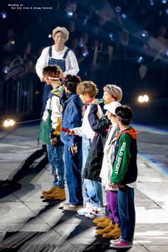 a group of young children standing on top of a stage with an adult in the background