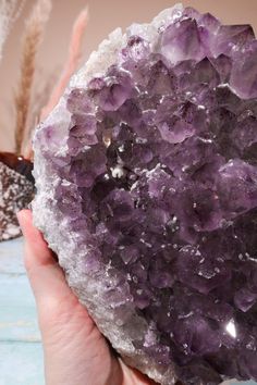 a person holding a rock with purple crystals on it