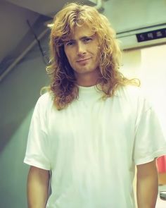 a man with long hair standing in front of a mirror wearing a white t - shirt