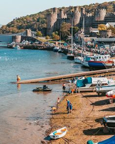 several boats are docked on the shore near an old castle