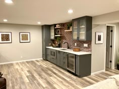 a kitchen with grey cabinets and white counter tops in a room that has wood flooring