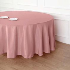 a round table with two white plates on it and a pink cloth draped over the top