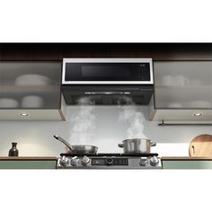 a stove top oven sitting inside of a kitchen next to pots and pans on the counter