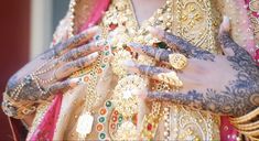 a close up of a person with henna on their hands and arms covered in jewelry