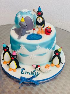 a birthday cake decorated with penguins and an elephant