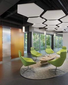 an office with green and yellow chairs, round coffee table, and circular light fixture