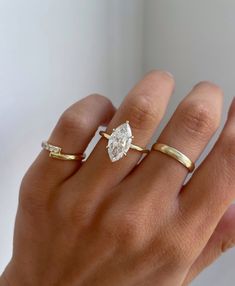 a woman's hand with two gold rings and a diamond ring on her finger