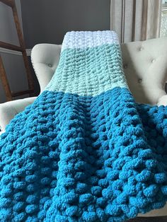 a blue crocheted blanket sitting on top of a white chair