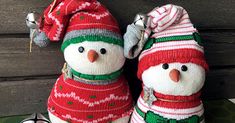 two knitted snowmen sitting next to each other on top of a green table