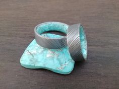 Turquoise rings, Raw Turquoise rings, December birthstone rings, Damascus steel bands, Male rings, Female rings, His and hers, Wedding band. 100% handmade jewelry. The rings in the photo is 7mm wide. This can be customized. This Damascus steel ring is forged by hand Available in all sizes (4-16) intermediate 1/4 Width from 3 mm to 9 mm. Customizing your ring does not have an additional cost. If you have any questions, contact me, I will give you a quick and friendly answer to all your questions. Round Patina Rings For Anniversary, Round Ring With Steel Shank For Gift, Round Steel Shank Rings As Gifts, Male Rings, Raw Turquoise Ring, Female Rings, Ring Green Stone, Damascus Ring, Damascus Steel Ring