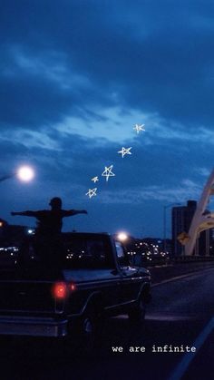 there is a man standing on the back of a truck in front of a bridge