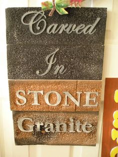 a stone sign hanging on the side of a door next to another sign that says carved in stone granite