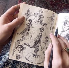 a person holding a pen and looking at an open book with drawings on the pages