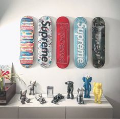 four skateboards mounted to the side of a wall above a shelf with toy figurines on it