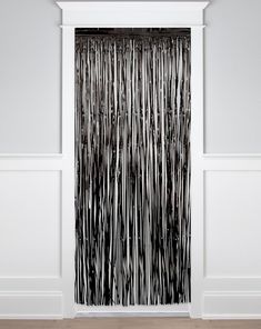 a black and white curtain hanging on the side of a wall next to a wooden floor