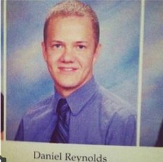 a man in a blue shirt and tie posing for a picture with his name on it