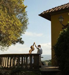 two people are standing on a balcony high fiving each other with their arms in the air