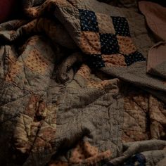 an unmade bed covered in quilts and blankets