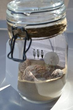 a glass jar filled with sand and sea shells