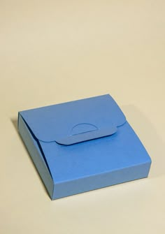 an open blue box on a white surface with no lid and paper in the bottom