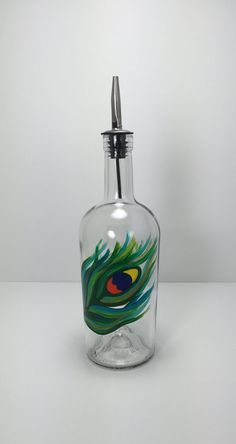 a glass bottle with a peacock design on the side and a pen in the top