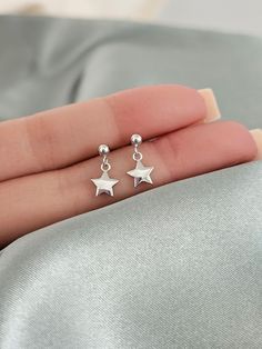 These sterling silver star dangle earrings are perfect for anyone who loves minimalistic style. An ideal gift for both kids and adults of all ages. They are made from hypoallergenic nickel free sterling silver to ensure that even those with sensitive skin can wear them without any irritation. Finish: platinum plated over sterling silver. Size: 3mm ball studs, 7mm star charms. Post size: 21 gauge, 11mm long Sold as a PAIR of two earrings. Comes with gift box ready for gift giving. Sterling silver Silver Sterling Earrings, Minimalist Star Charm Earrings As Gift, Simple Silver Earrings Star, Cute Silver Star Jewelry, Tiny Gift Ideas, Dainty Silver Star Earrings, Silver Star Earrings With Charms, Cheap Silver Star-shaped Piercings, Cute Silver Earrings