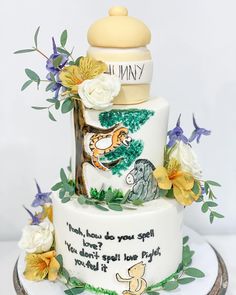 a three tiered cake with winnie the pooh on top and flowers around it