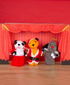 three stuffed animals are standing in front of a red curtain