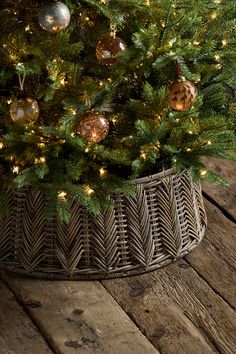 a small christmas tree in a basket on a wooden floor