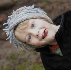 a young boy wearing a knitted hat and looking up at the camera with his eyes wide open