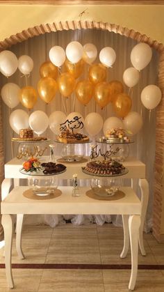 a table topped with lots of balloons next to a white table covered in cake and desserts