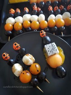 two black plates topped with halloween treats and marshmallows on skewers