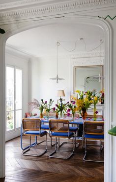 a dining room table with chairs and flowers in vases