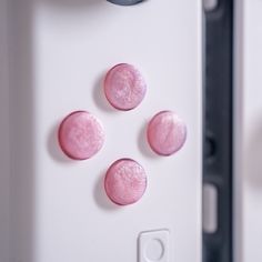 four pink buttons on the side of a white controller