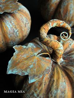 three pumpkins with leaves on them sitting next to each other in front of a black background