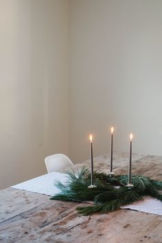 a wooden table topped with candles and greenery