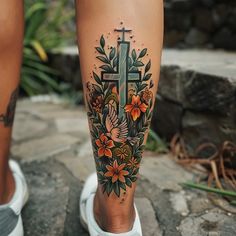 a woman's leg with flowers and a cross tattoo on her left calf area