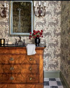 a bathroom with a wooden dresser, mirror and wallpaper on the walls behind it