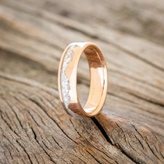 a close up of a wedding ring on top of a piece of wood with white diamonds in it