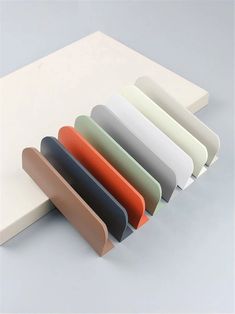 an assortment of different colored papers on a white surface with one folded over the edge