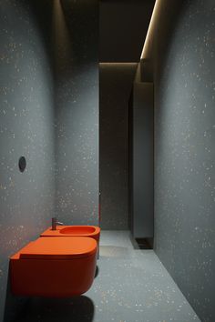 an orange sink in the middle of a room with black walls and flooring on it