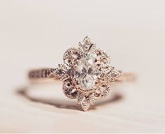 an engagement ring with a flower design on it's center and side stones in the middle