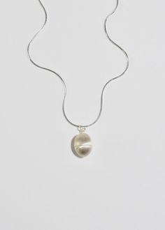 Sterling egg pendant necklace with a screw mechanism and hollow center to store a talisman. It is designed for the wearer to carry around a special, personal object to hold close to your heart — akin to a locket. Contains petite freshwater seed pearls. Each piece is hand carved, cast, and finished in New York by Owen Dunton of Dunton Ellerkamp. Available in a 16" solid snake chain or an 18" delicate oval chain. Material: Sterling silver. We recommend storing in a dry place and periodic polishing Sterling Silver Oval Pearl Drop Necklace, Silver Necklace With Oval Pearl Charm Pendant, Minimalist Oval Pendant Necklace For Keepsake, Minimalist Oval Pearl Pendant Jewelry, Minimalist Oval Pendant Necklace As Keepsake, Silver Oval Necklace With Pearl Drop, Silver Oval Pearl Drop Necklace, Silver Jewelry With Pearl Charm In Oval Pendant, Silver Jewelry With Oval Pendant And Pearl Charm